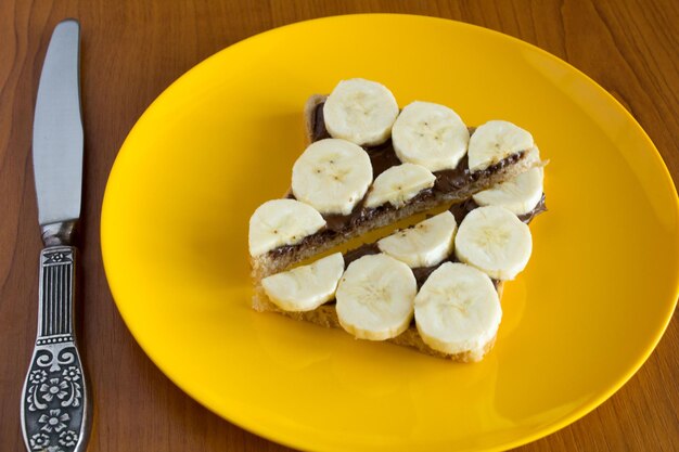 Tostadas en rodajas con crema de chocolate y plátano en el plato amarillo