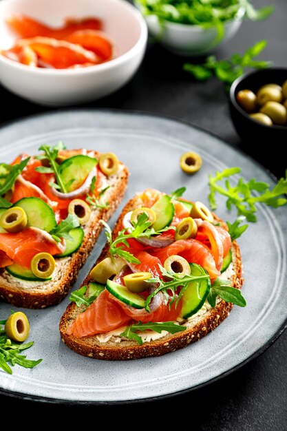 Tostadas con salmón salado rúcula aceitunas verdes y pepino