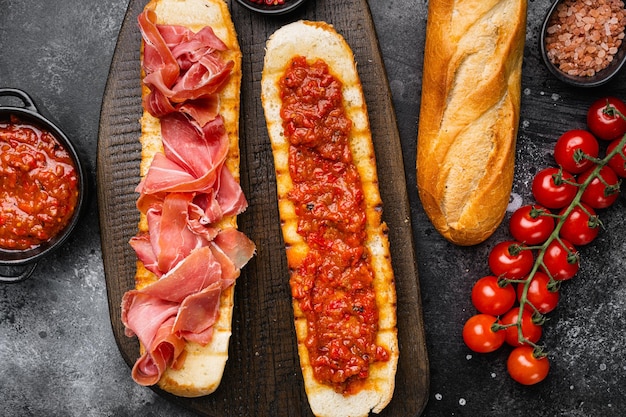 Tostadas de tomate y jamón español sobre fondo de mesa de piedra oscura negra vista superior plana