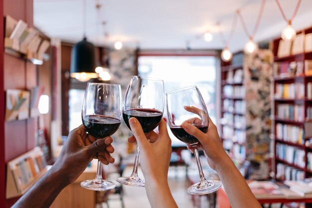 Tostado con las manos levantadas sosteniendo copas en un café de libros - celebración