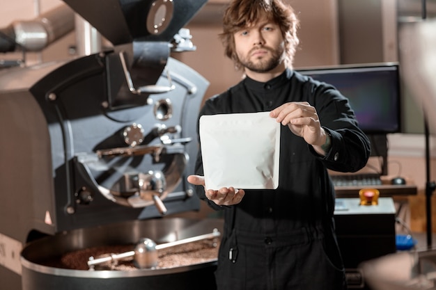 Tostador hombre profesional presenta un paquete de café