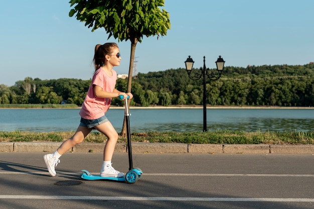 Totale des Mädchens auf blauem Roller