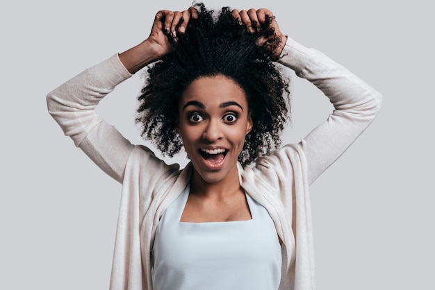 Totalmente loco. Juguetón joven africana con la boca abierta manteniendo las manos en el cabello