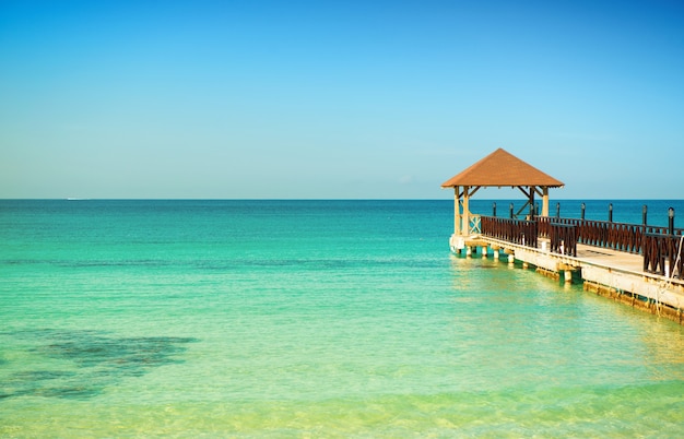 Totenstill. Hölzerner Pier, türkisfarbenes Meer, blauer Horizont und klarer wolkenloser Himmel.