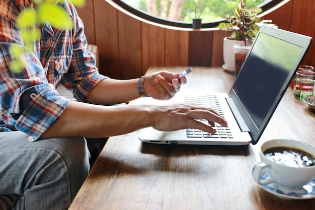 Foto touch screen der frauen und schreibender laptop des mannes auf hölzerner tabelle