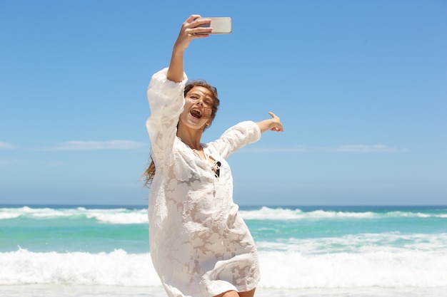 Toung mujer tomando selfie divertido en la playa