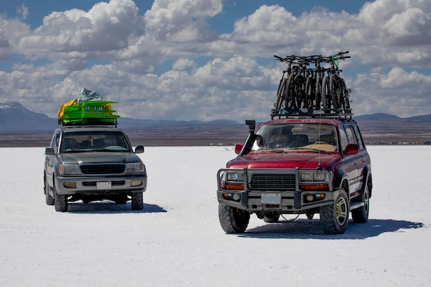 Foto tour in zwei geländewagen mit untergetauchten fahrrädern auf dem salar de uyuni