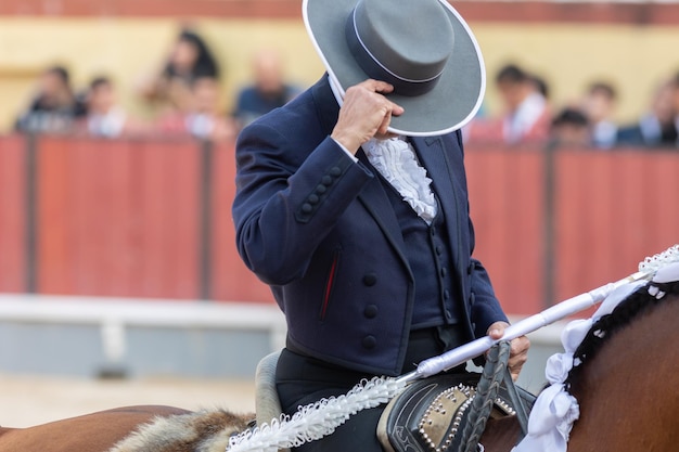 Foto tourada caballeiro a caballo cubre su rostro con su sombrero