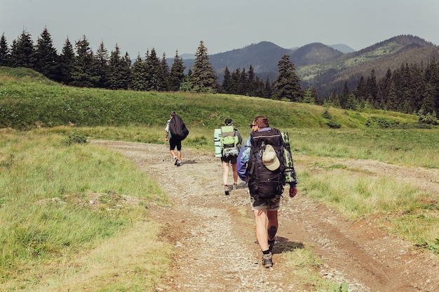 Foto tourismus, berge, lifestyle, natur, menschenkonzept - eine gruppe von wanderern mit rucksäcken geht auf einem weg zu einem bergrücken. backpacker-stil. konzept der aktiven freizeitgestaltung..