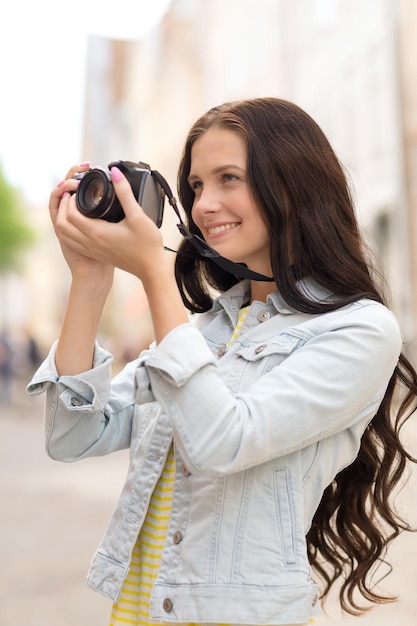 Tourismus, Reisen, Freizeit, Urlaub und Freundschaftskonzept - lächelndes Teenager-Mädchen mit Kamera, das auf der Straße fotografiert