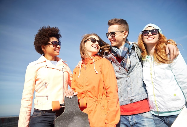 Tourismus, Reisen, Menschen, Freizeit- und Jugendkonzept - Gruppe glücklicher Freunde mit Sonnenbrillen, die sich auf der Straße der Stadt umarmen und unterhalten