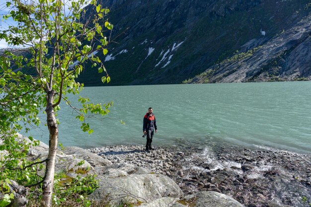 Tourist am Gletschersee Nigardsbreen mit Kamera in der Hand in Norwegen