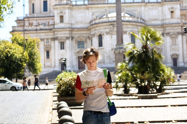 Tourist, der auf eine Karte schaut, junger Mann, der in der Stadt spazieren geht