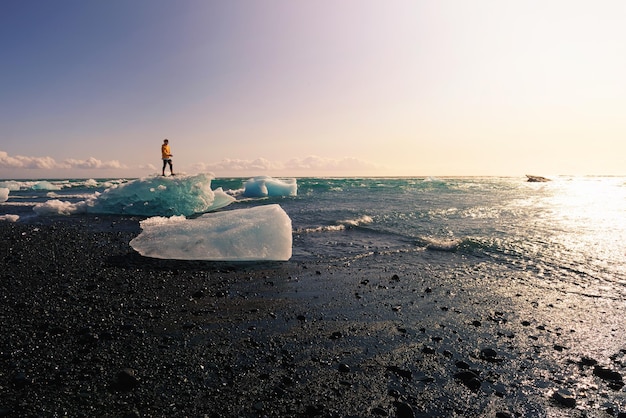 Tourist, der auf einem Eisberg am Diamond Beach Island steht