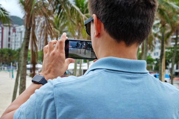 Tourist, der auf handy der copacabana schießt