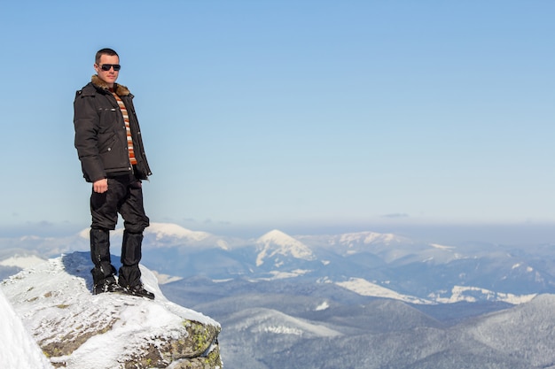 Tourist, der auf schneebedecktem Berggipfel steht