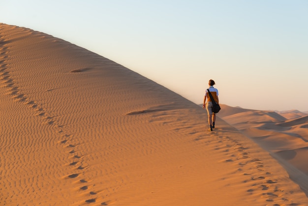 Tourist, der auf szenische Dünen in der Namibischen Wüste, Namibia geht