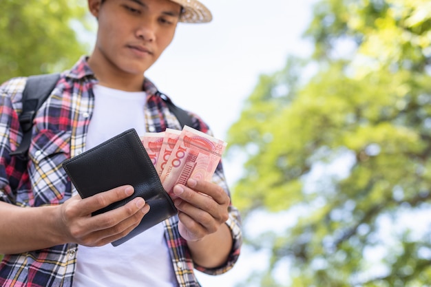 Tourist, der Banknote in der schwarzen Geldbörse zählt oder überprüft, die er in der Touristenattraktion fand