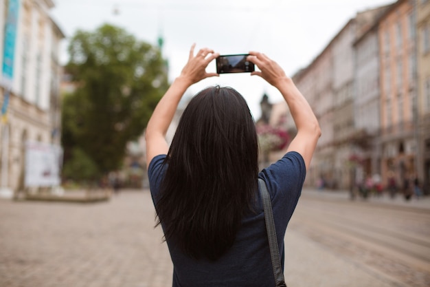 Tourist, der durch das Stadtzentrum von Lvov geht und ein Foto auf ihrem Handy macht