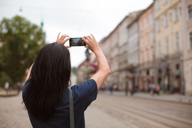 Tourist, der durch die Innenstadt spaziert und mit ihrem Handy fotografiert. Platz für Text