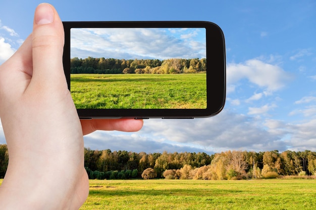 Tourist, der im Herbst ein Foto der grünen Wiese macht