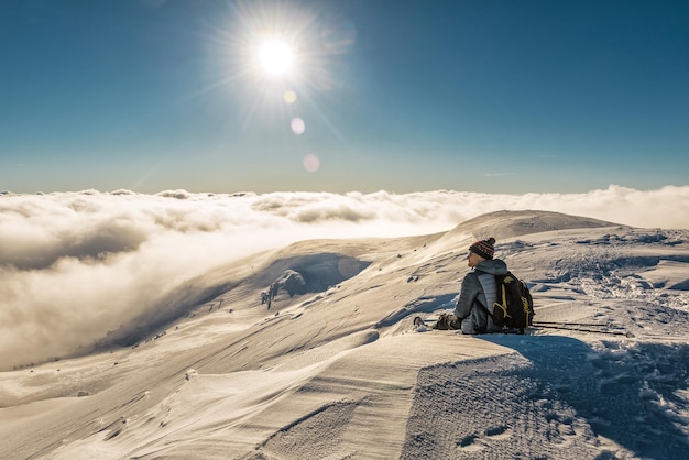 Tourist, der in den schneebedeckten Karpaten über den Wolken ruht