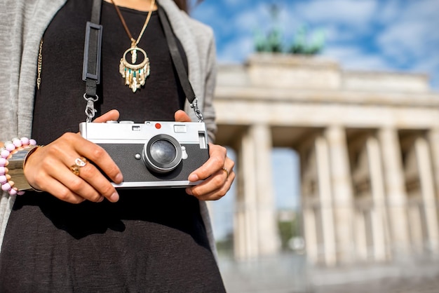 Tourist der jungen Frau, der mit Fotokamera vor den berühmten Brandenburger Toren in Berlin steht