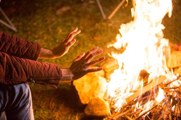 Foto tourist, der seine hände über dem lagerfeuer in den bergen aufwärmt.