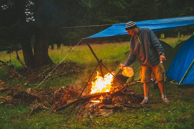 Tourist entzündet Feuer. Der Reisende zündet im Lager Feuer an. Mann am Lagerfeuer.