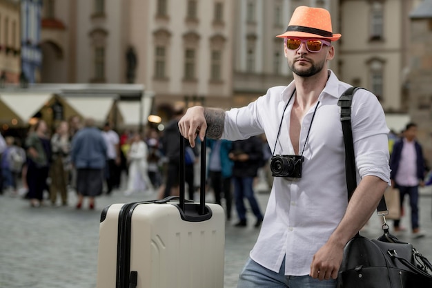 Tourist im Urlaub Mann Reisender mit Reisetasche Outdoor-Porträt eines jungen kaukasischen Mannes mit Hut und s