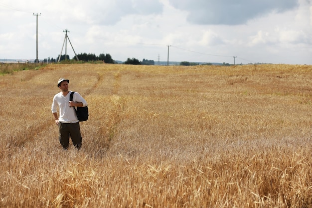 Foto tourist in einem feld von getreidepflanzen. ein mann auf einem weizenfeld. getreideernte.