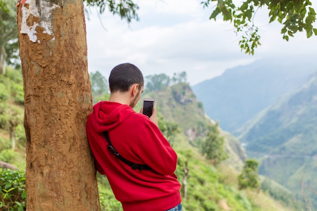 Tourist kerl, der bilder der natürlichen landschaft am telefon macht