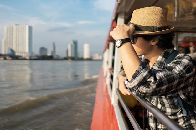 Tourist mit Hut, der in einem Boot am Fluss steht
