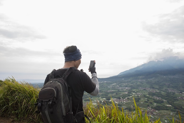 Tourist mit Rucksack macht Fotos mit Smartphone in den Bergen