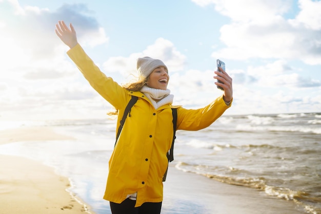 Tourist mit Telefon Selfie Zeit Tourist in gelber Jacke posiert am Meer bei Sonnenuntergang Reisen