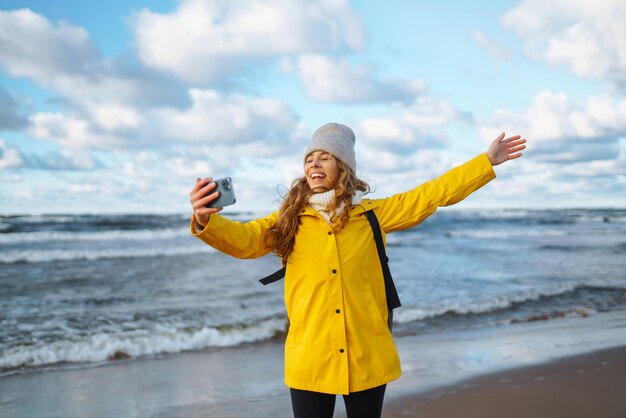 Tourist mit Telefon Selfie-Zeit Tourist in gelber Jacke posiert am Meer bei Sonnenuntergang Reisen