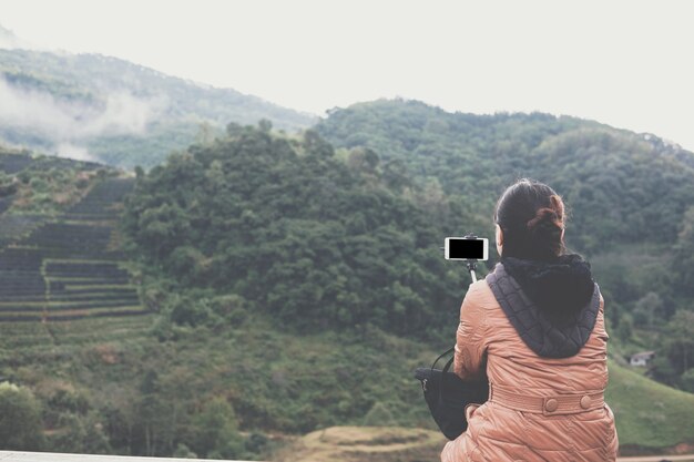 Tourist verwenden Smartphone, um Selfie-Foto mit Blick auf die Berge zu machen.