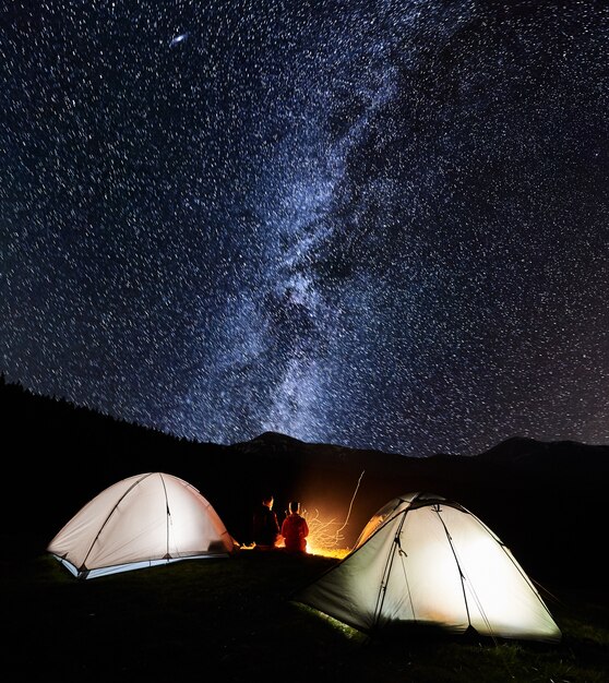 Touristen am Lagerfeuer in der Nähe von Zelt in der Nacht