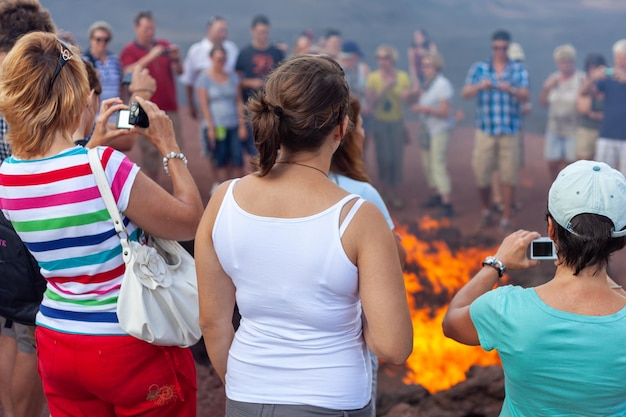 Foto touristen beobachten das feuer eines vulkans im nationalpark timanfaya auf der spanischen insel lanzarote