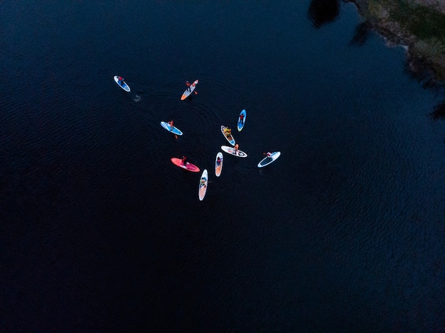 Touristen, die auf SUP-Board im blauen Meer schwimmen. Draufsicht auf eine Gruppe von Menschen auf SUP-Boards, die im ruhigen klaren Meer schwimmen floating