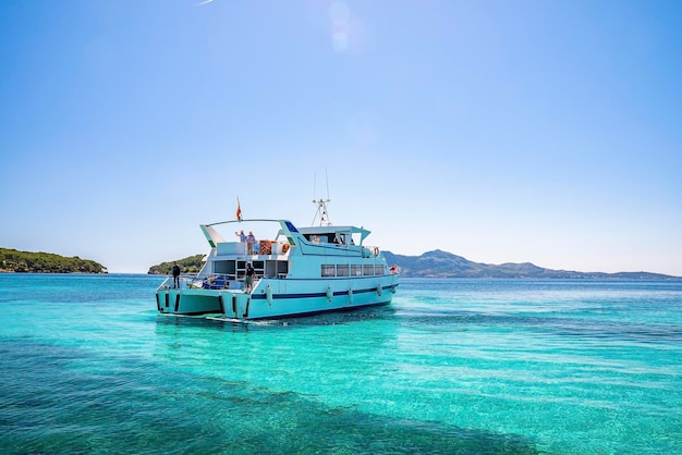 Touristen, die im Sommer auf dem türkisfarbenen Meer der Yacht gegen den klaren blauen Himmel segeln