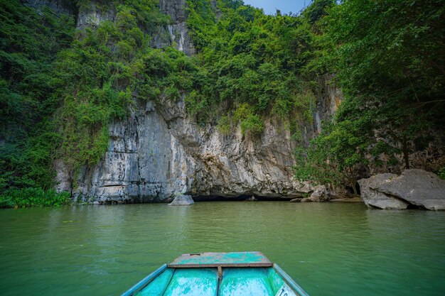 Foto touristen, die in booten entlang des ngo-dong-flusses im tam-coc-bereich der provinz ninh binh reisen, vietnams ruderer, die ihre füße verwenden, um ruder zu treiben landschaft, die von karsttürmen und reisfeldern gebildet wird