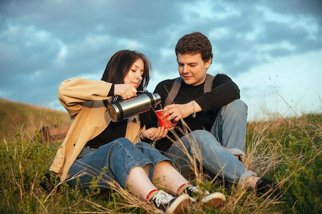 touristen ein mann und ein mädchen im urlaub während einer reise trinken kaffee aus einer thermoskanne