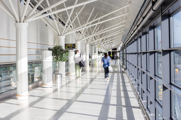 Touristen gehen zu verschiedenen Toren, indem Sie dem Gate-Label mit Pfeil im Terminal des Flughafens folgen