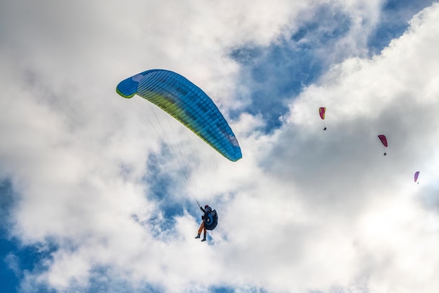 Touristen praktizieren Paragliding-Aktivsport im Hochland gegen riesige Waldberge, die an sonnigen Herbsttagen von hellem Sonnenlicht beleuchtet werden