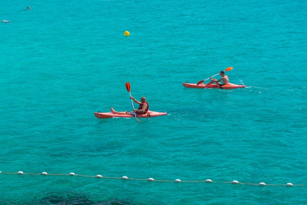 Touristen schwimmen auf Katamaranen und Kajaks in der beliebten Bucht des Mittelmeers.