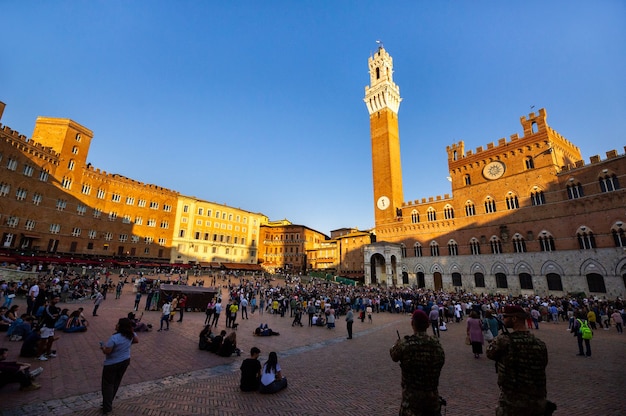 Touristen spazieren durch die Piazza del Campo in Siena