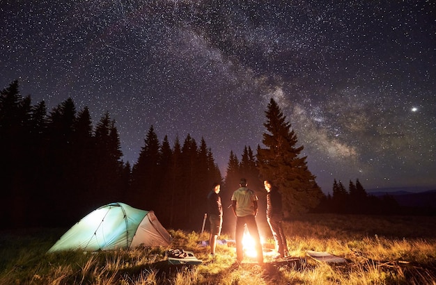 Touristen stehen am Lagerfeuer im Nachtwald