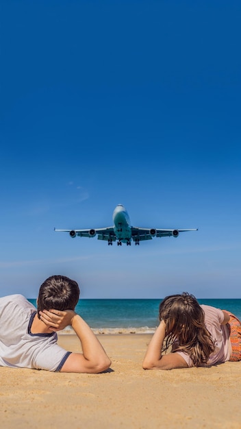 Touristen von Mann und Frau haben Spaß am Strand und beobachten die landenden Flugzeuge, die in einem Flugzeug reisen