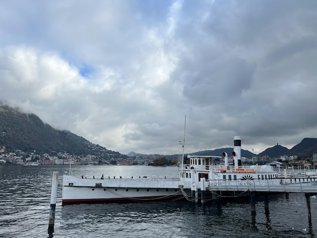 Foto touristenboot steht am pier am see vor der kulisse einer hohen bergkette in como, italien